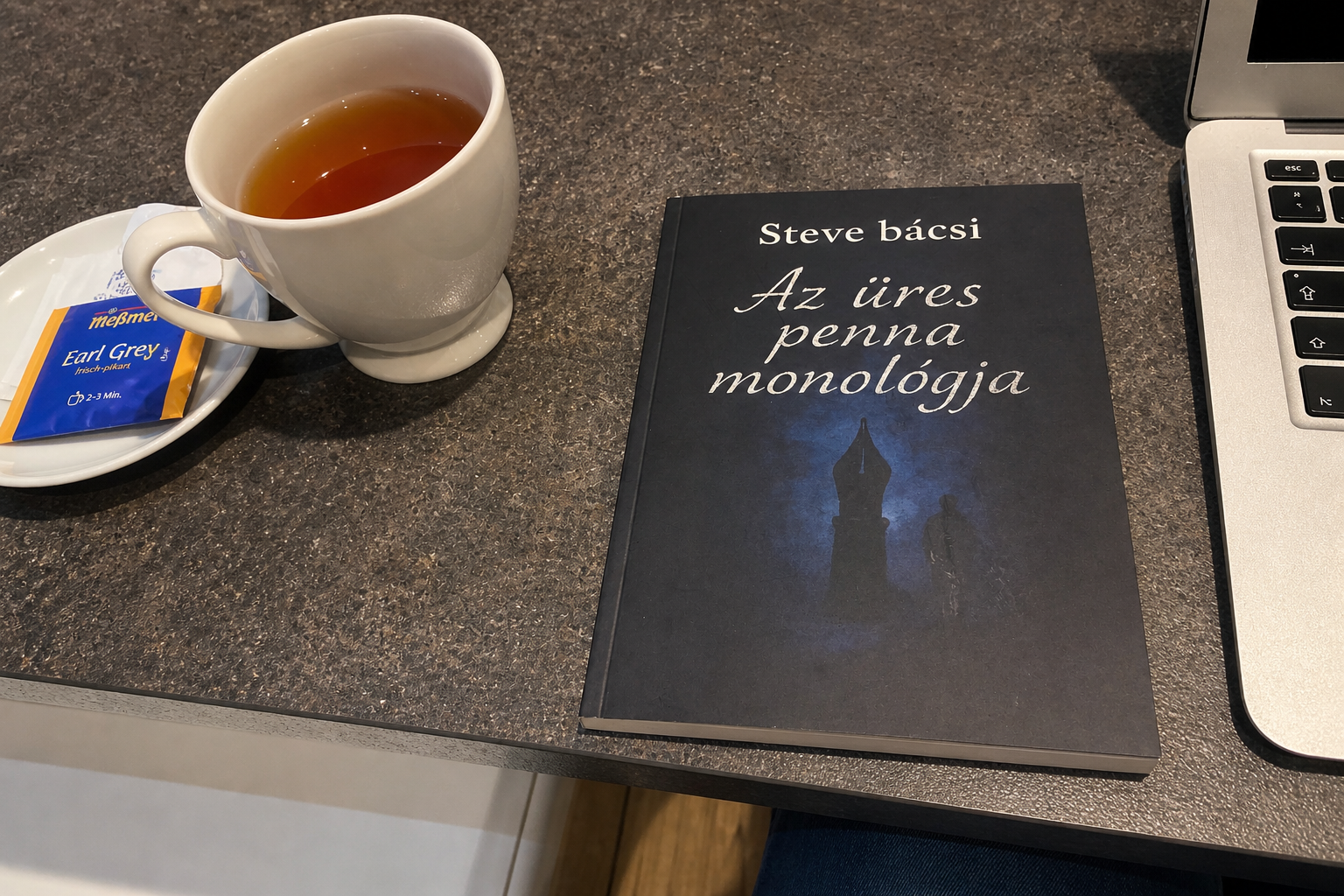 Cup of tea next to Steve bácsi’s poetry book Az üres penna monológja on a table with a laptop, cozy reading scene
